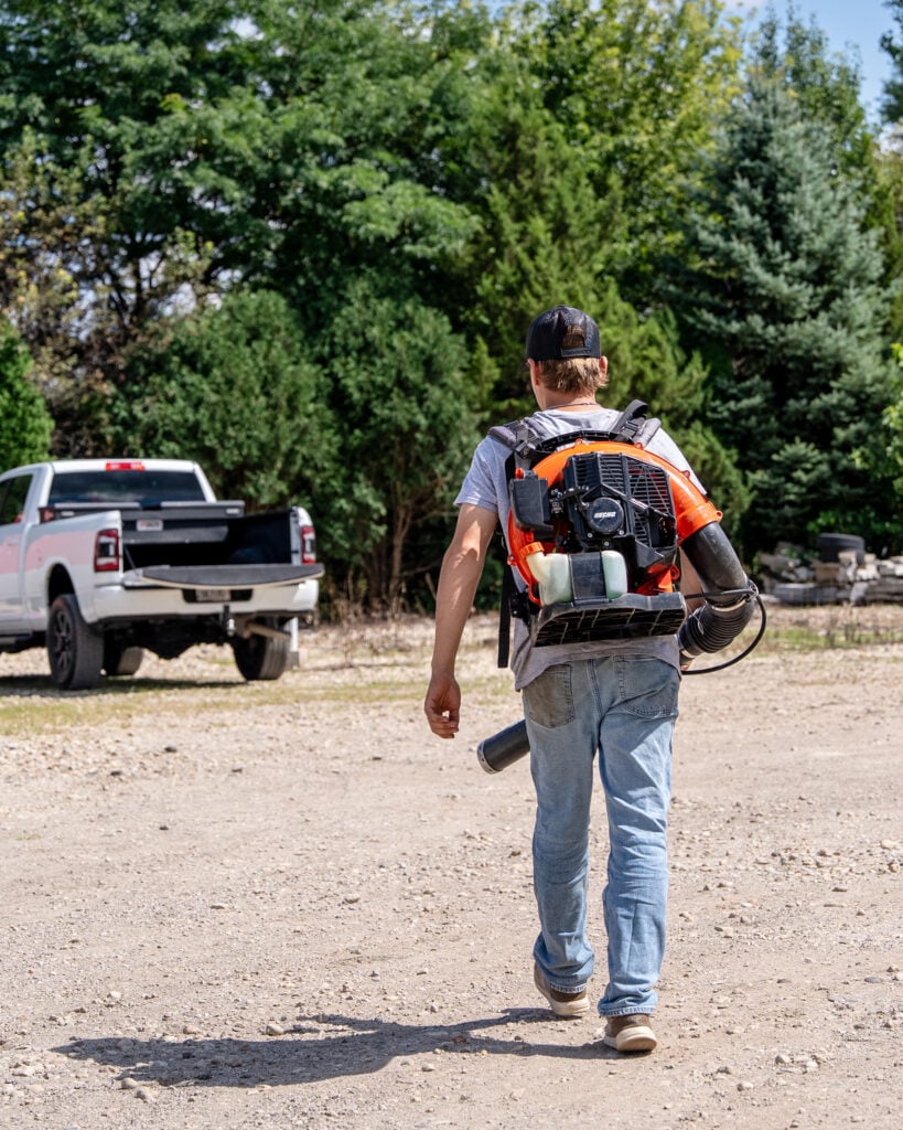 HLM crew member walking back to the truck with a backpack blower
