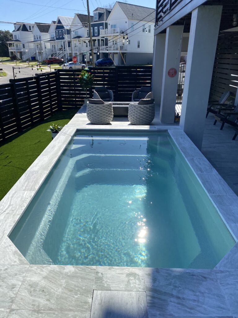Partially in-ground Little Pool Co fiberglass pool finished with dark cladding panels
